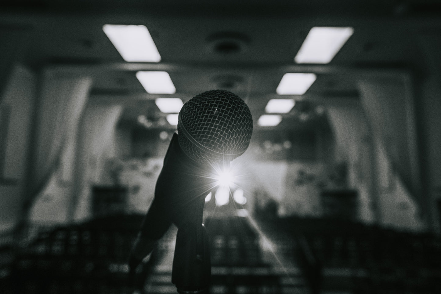 A focused shot of a microphone with a bright backlight in an empty auditorium, evoking the anticipation before comedy shows—highlighting Donate by San Diego Comedy and its role in supporting the vibrant local comedy community.