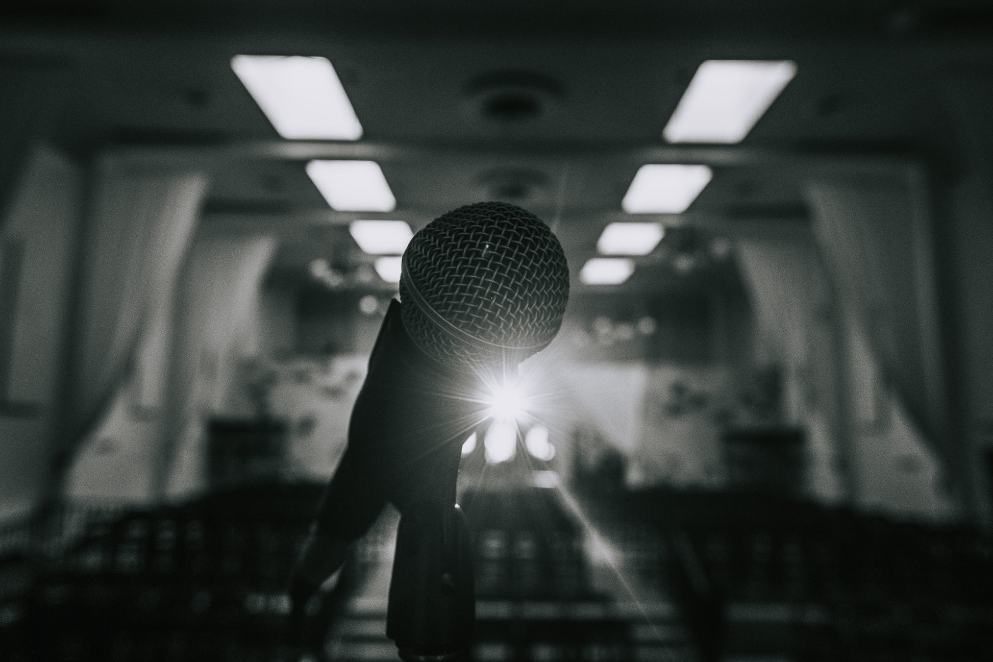 A focused shot of a microphone with a bright backlight in an empty auditorium, evoking the anticipation before comedy shows—highlighting Donate by San Diego Comedy and its role in supporting the vibrant local comedy community.